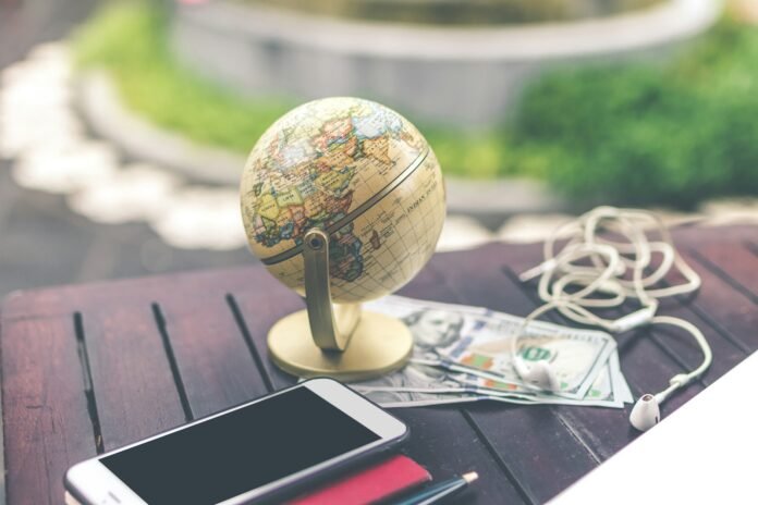 Globe beside dollar bills and a smartphone, representing international remittances to Africa