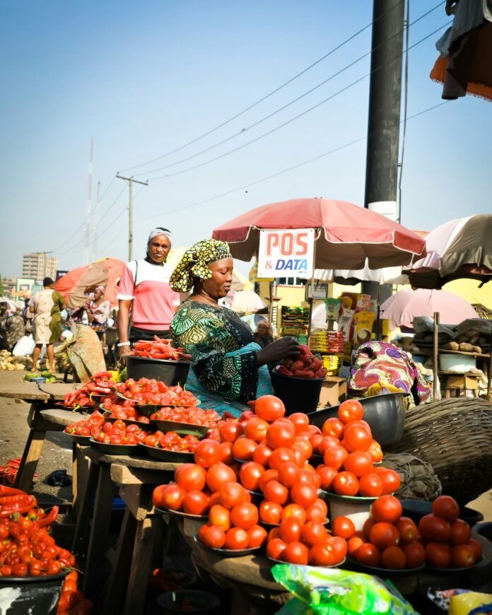 Shoppers at an African food market buying tomatoes, illustrating Nigeria's food inflation slowdown