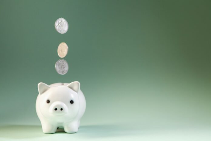 Coins falling into a piggy bank, illustrating savings and how inflation affects real returns