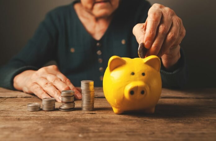 Hands depositing coins into a piggy bank, representing pension and retirement savings
